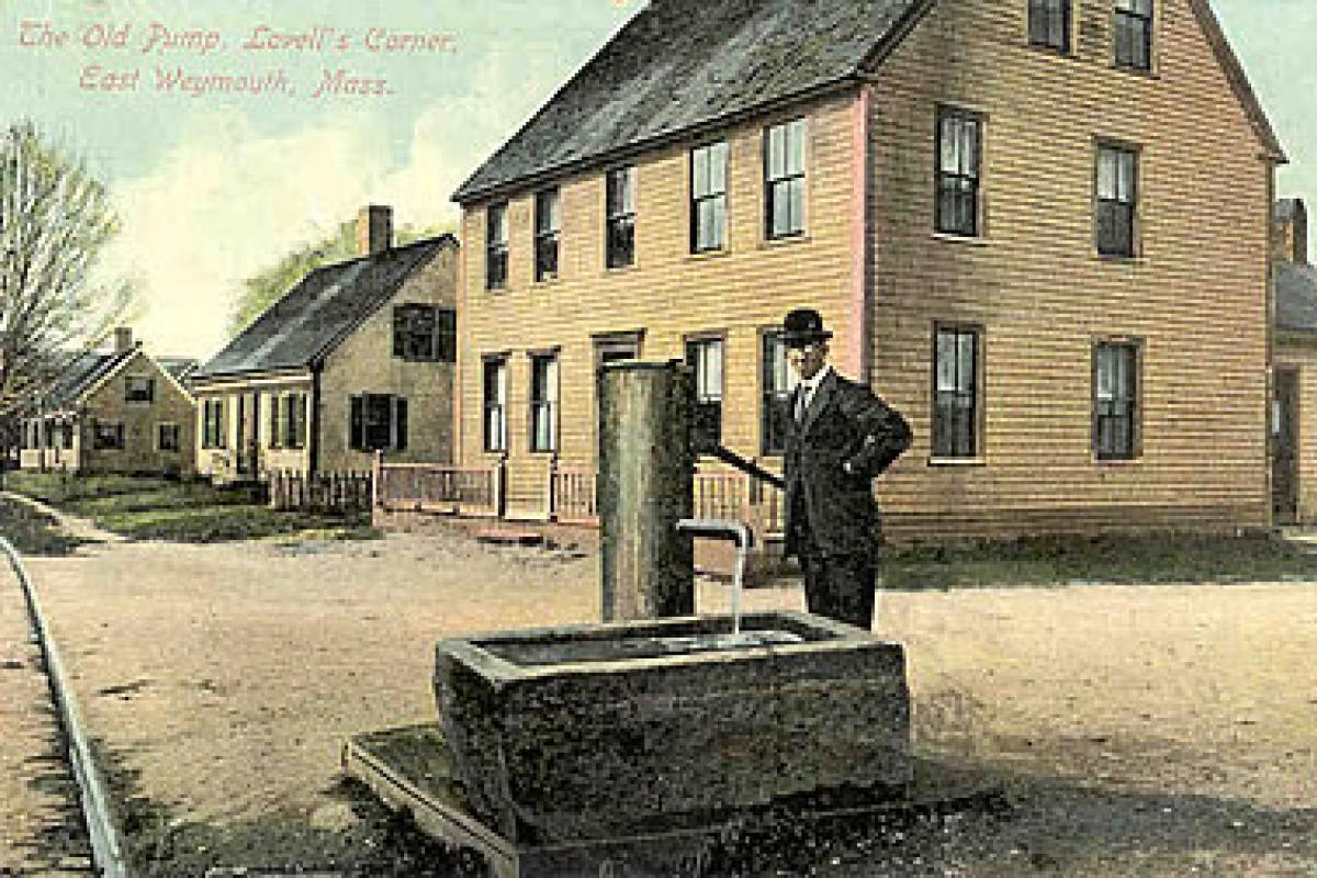 The Old Pump, Lovell's Corner, East Weymouth MA. The two houses in the background, on the left hand side are still there today. Image provided by the William and Elaine Pepe postcard collection.